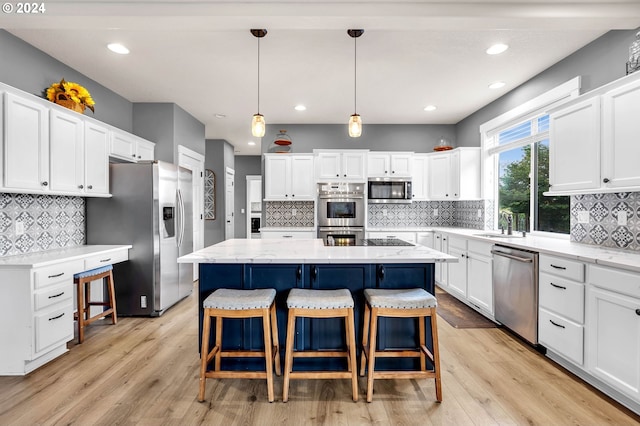 kitchen featuring white cabinetry, hanging light fixtures, a center island, stainless steel appliances, and light hardwood / wood-style flooring