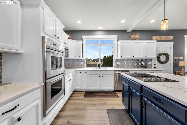 kitchen with appliances with stainless steel finishes, blue cabinetry, white cabinets, and light stone counters