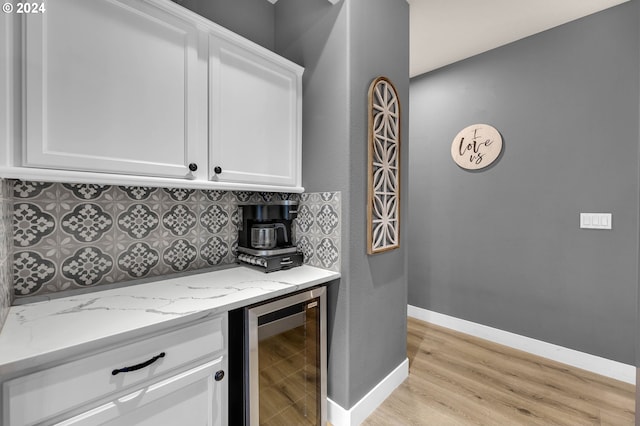 bar with light stone counters, backsplash, beverage cooler, and white cabinets