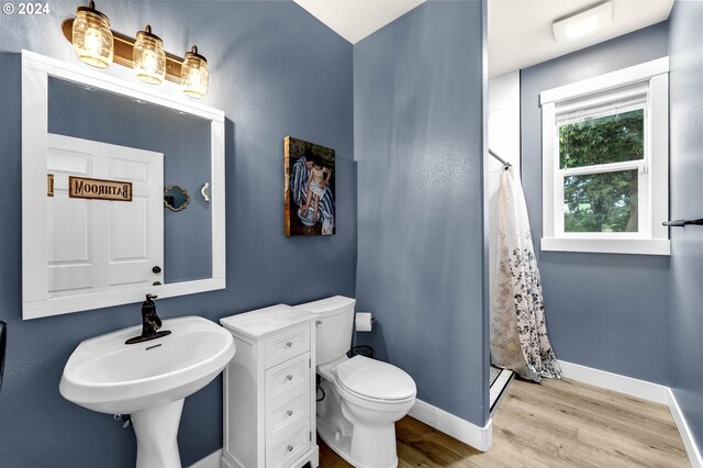 bathroom featuring curtained shower, hardwood / wood-style flooring, and toilet