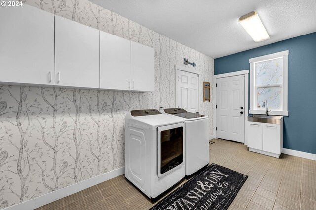 washroom featuring a textured ceiling, washing machine and dryer, cabinets, sink, and light tile patterned flooring