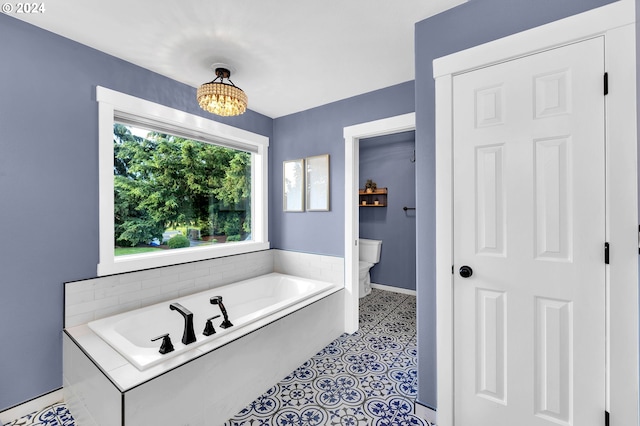 bathroom featuring a notable chandelier, a bathing tub, and toilet