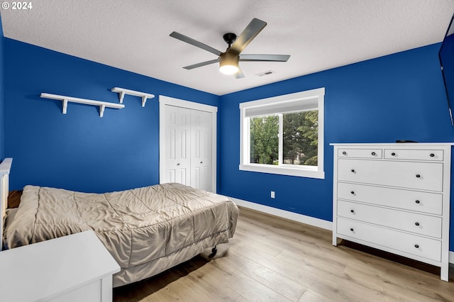 bedroom with a closet, ceiling fan, light hardwood / wood-style floors, and a textured ceiling