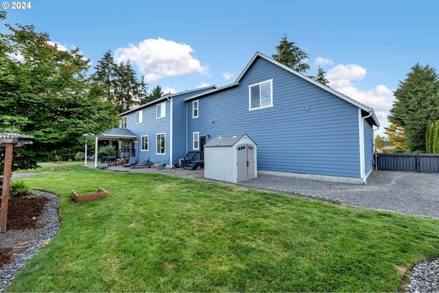 rear view of house featuring a patio area, a yard, and a shed