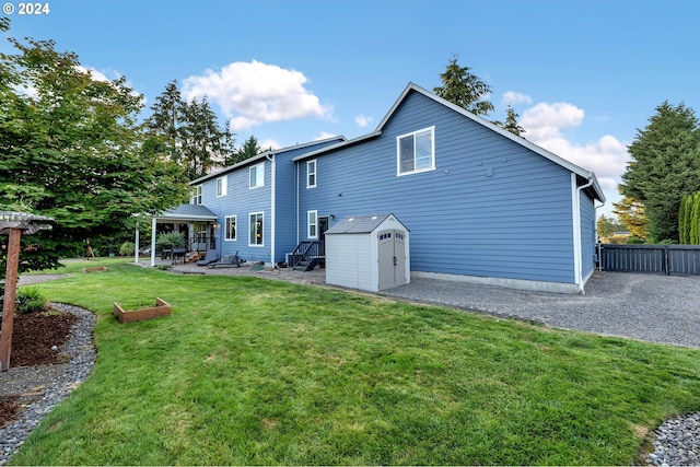 rear view of house featuring a yard, a patio, and a storage unit