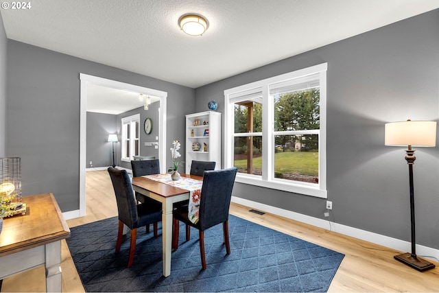 dining area with hardwood / wood-style floors and a textured ceiling