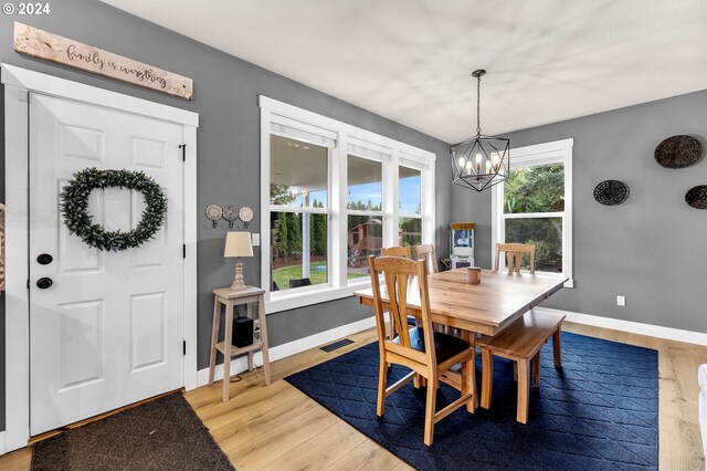 dining space with wood-type flooring, plenty of natural light, and a notable chandelier