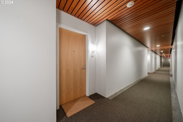 corridor featuring dark colored carpet and wooden ceiling