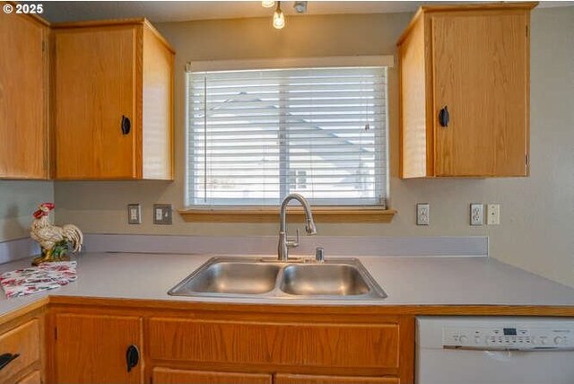 kitchen with white dishwasher, light countertops, and a sink