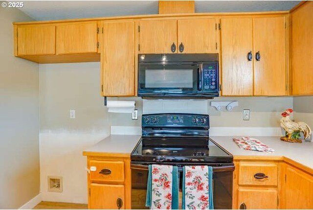 kitchen featuring light countertops, baseboards, and black appliances