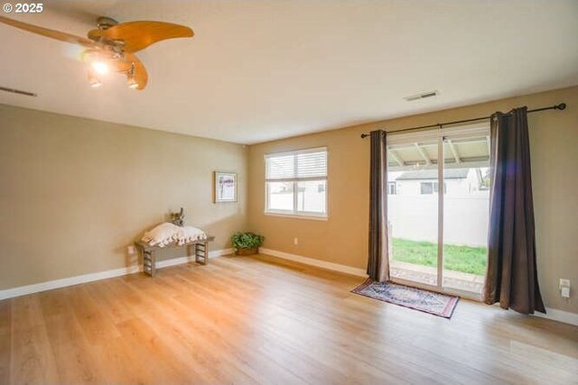 empty room featuring a ceiling fan, baseboards, visible vents, and light wood finished floors