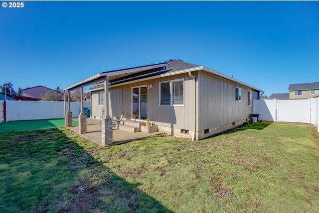 back of property with crawl space, a patio area, a fenced backyard, a yard, and solar panels