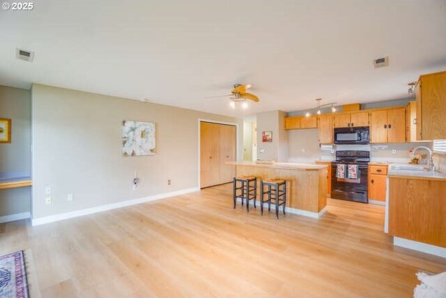 kitchen featuring light wood-style flooring, ceiling fan, a sink, and black appliances