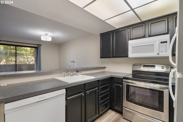 kitchen featuring white appliances, kitchen peninsula, sink, and light hardwood / wood-style flooring