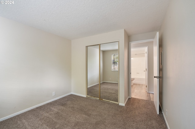 unfurnished bedroom with carpet floors, a closet, and a textured ceiling