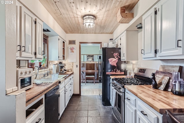 kitchen with black dishwasher, gas range, dark tile patterned floors, wood counters, and white cabinets