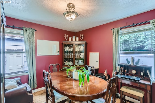 dining space featuring light wood-type flooring and a textured ceiling