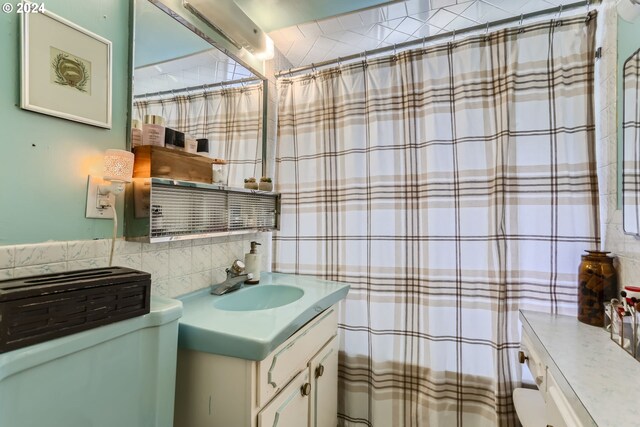 bathroom with vanity, tile walls, toilet, and backsplash