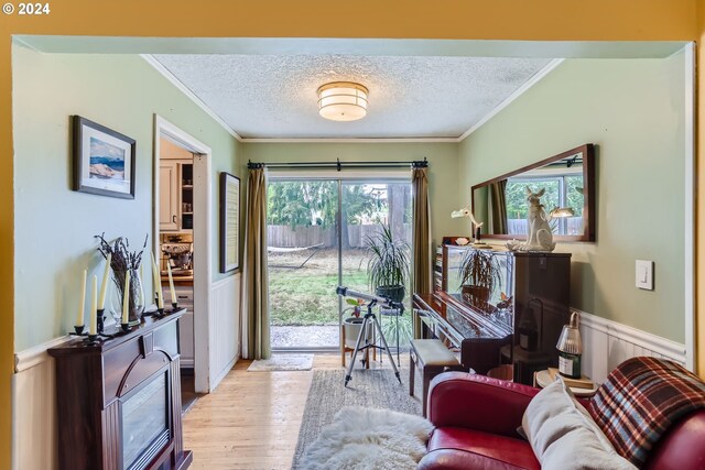 living room with a wealth of natural light, a textured ceiling, light hardwood / wood-style floors, and crown molding