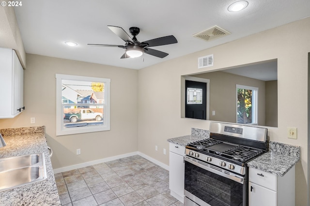 kitchen featuring light stone countertops, white cabinetry, sink, and stainless steel gas range