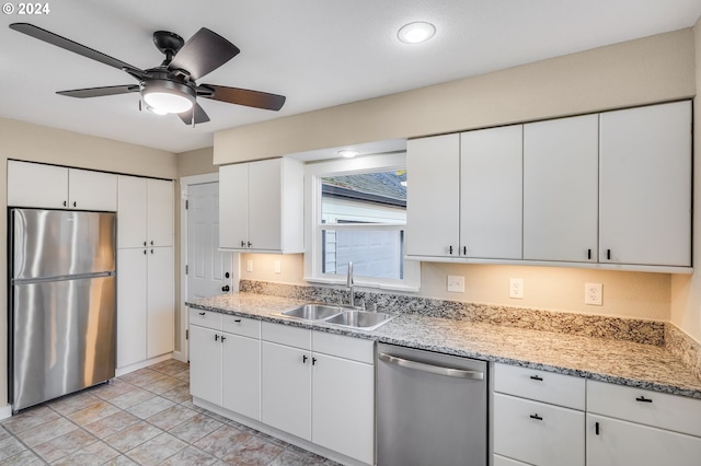 kitchen featuring light stone countertops, stainless steel appliances, white cabinets, ceiling fan, and a sink