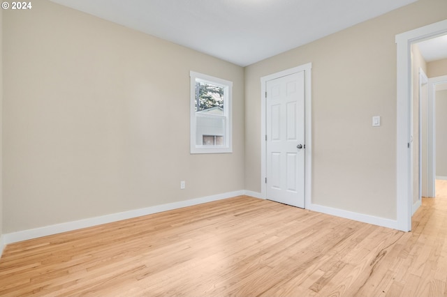 spare room featuring baseboards and light wood-type flooring