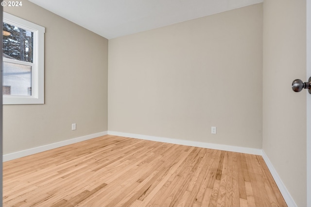 spare room with baseboards and wood finished floors