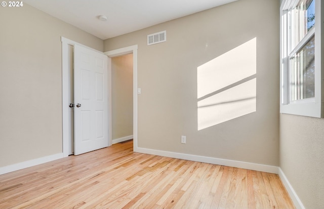 unfurnished room with baseboards, visible vents, wood finished floors, and plenty of natural light