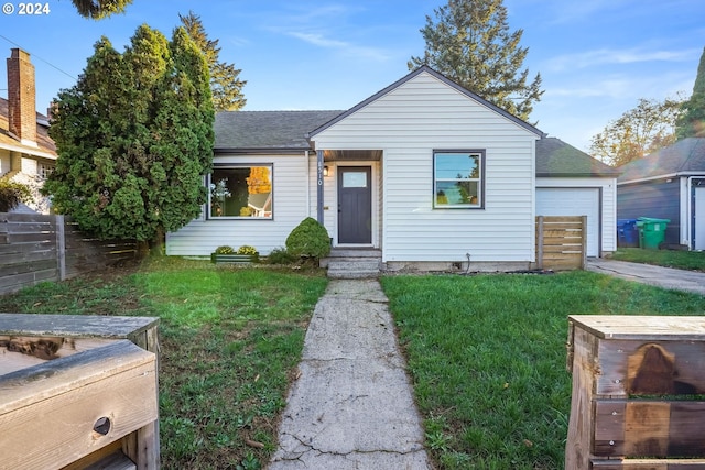 view of front of house featuring a garage, a shingled roof, fence, and a front lawn