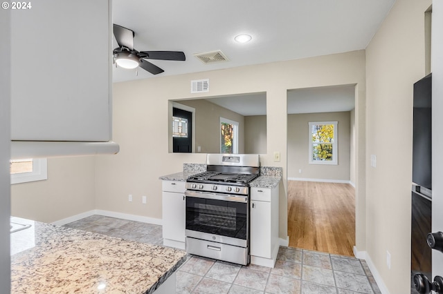 kitchen with stainless steel range with gas cooktop, visible vents, a ceiling fan, and white cabinets