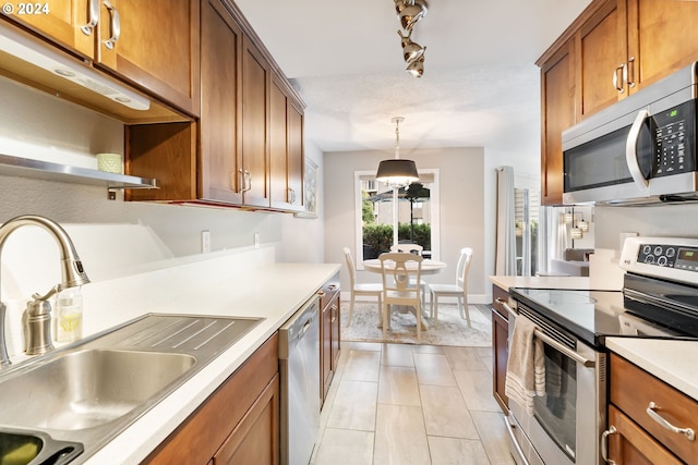 kitchen with decorative light fixtures, stainless steel appliances, light tile patterned floors, and sink