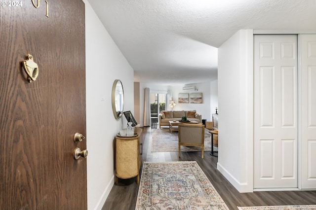 entrance foyer featuring a textured ceiling, dark hardwood / wood-style flooring, and an AC wall unit