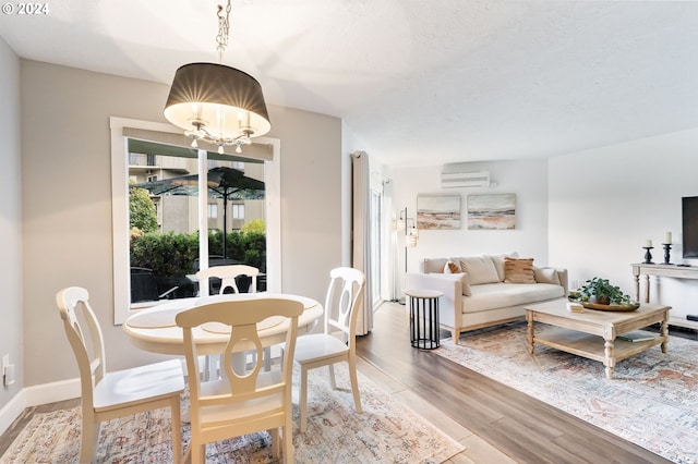 dining room with hardwood / wood-style floors, a wall mounted AC, and a notable chandelier