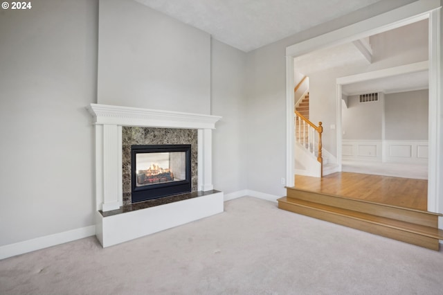 unfurnished living room featuring a high end fireplace and carpet flooring