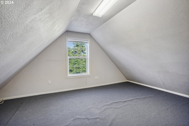 bonus room with carpet floors, vaulted ceiling, and a textured ceiling