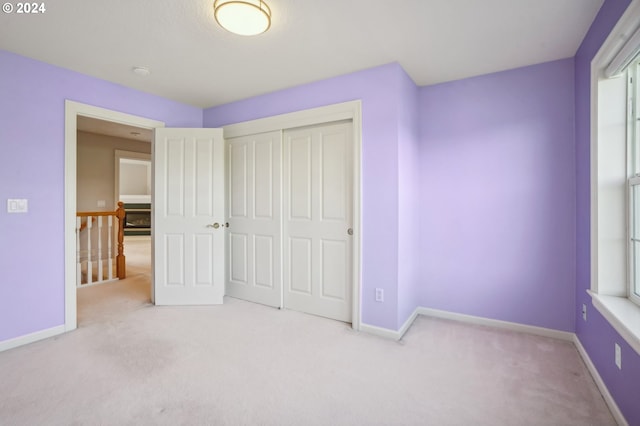 unfurnished bedroom featuring light carpet and a closet