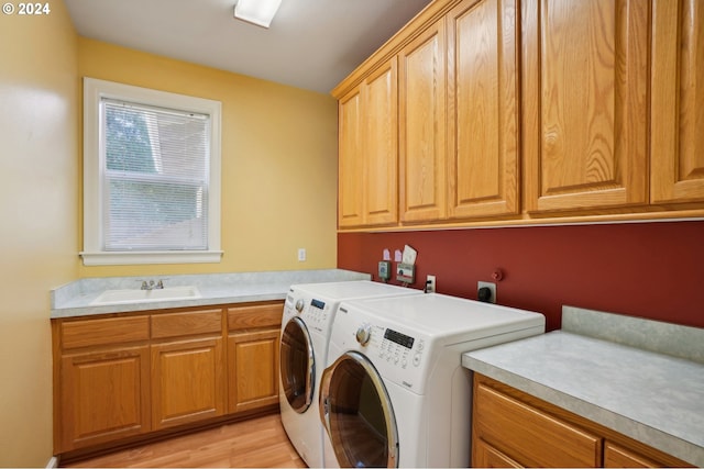 clothes washing area featuring light hardwood / wood-style flooring, washer and dryer, cabinets, and sink