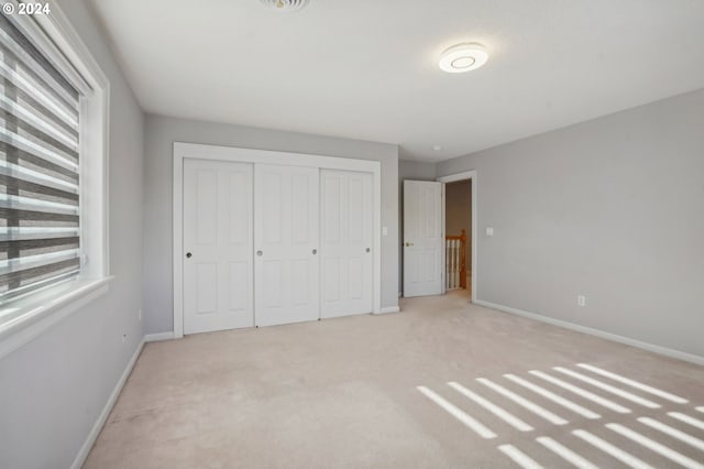 unfurnished bedroom featuring a closet and light carpet