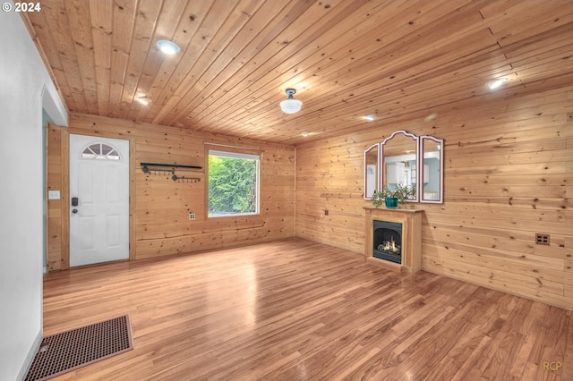 unfurnished living room with wooden walls, light hardwood / wood-style flooring, and wood ceiling