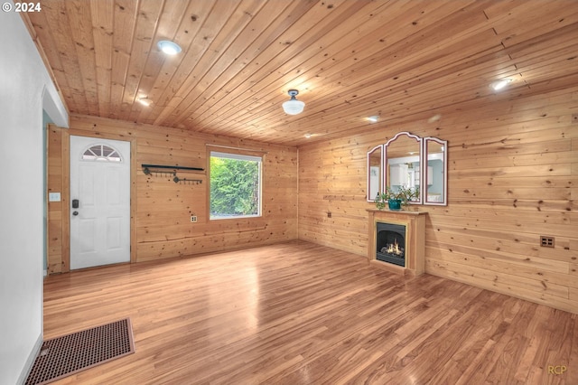 33062 Bellcrest Rd, Scappoose, OR 97056 - unfurnished living room with a warm lit fireplace, light wood-type flooring, wood ceiling, and wood walls