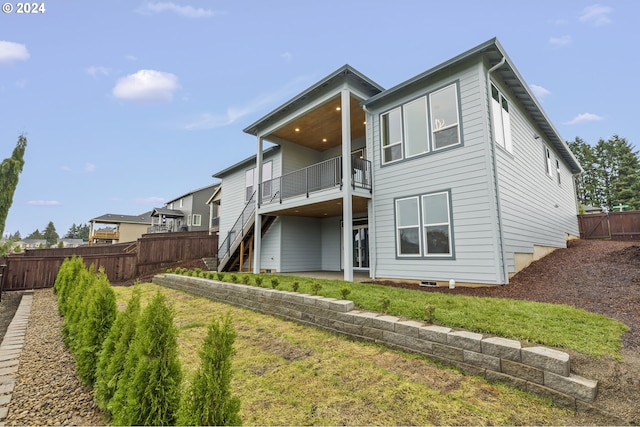 back of house with a wooden deck, a patio, and a yard