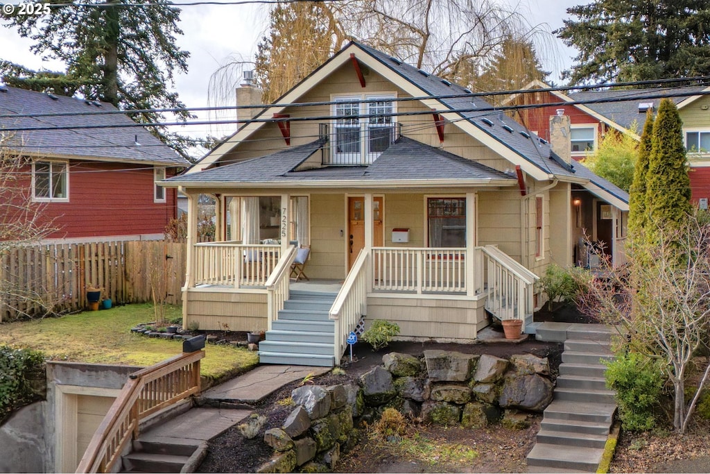 bungalow-style house featuring a porch, a balcony, and a front lawn