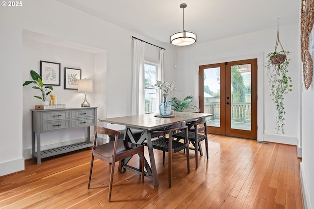 dining area featuring light wood finished floors, plenty of natural light, baseboards, and french doors