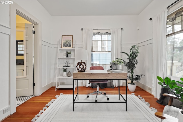 office featuring wainscoting, wood finished floors, and a decorative wall