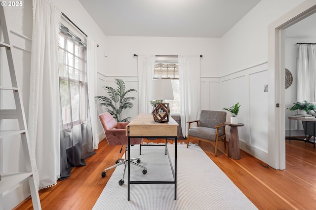 office space with a wainscoted wall, a decorative wall, and wood finished floors