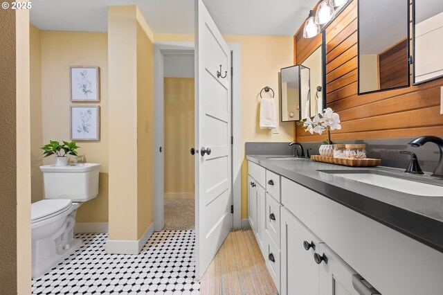 full bathroom featuring double vanity, a sink, toilet, and baseboards