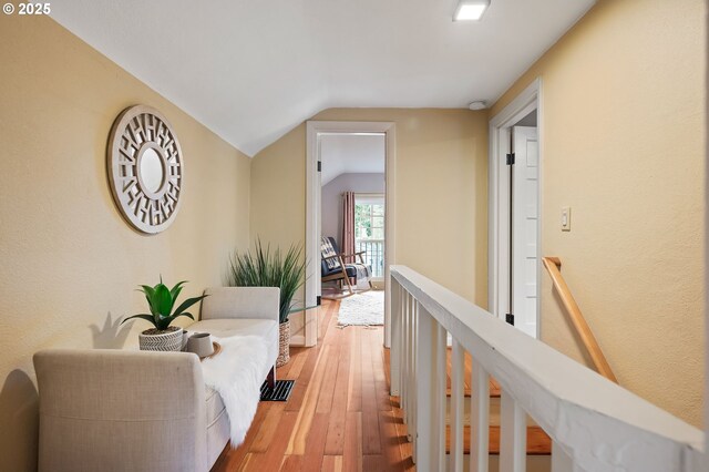 hallway featuring vaulted ceiling, wood finished floors, and an upstairs landing