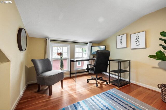 office space with vaulted ceiling, baseboards, and wood finished floors