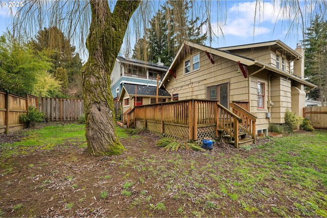 back of property with a fenced backyard, a chimney, and a deck