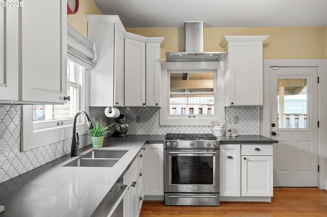 kitchen featuring a sink, white cabinets, gas stove, range hood, and dark countertops